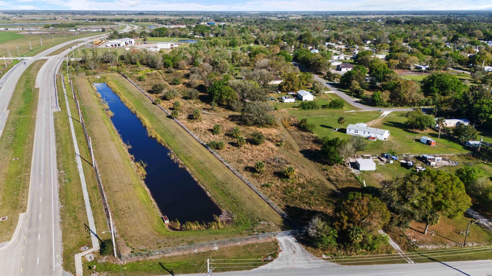An aerial view shows a rectangular retention pond next to a highway and residential area — 0 NE 60th & 64th Avenue, Okeechobee FL 34974, OKEECHOBEE, FL