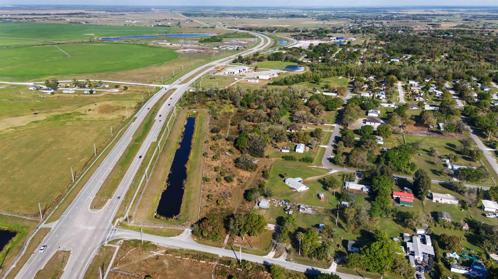 An aerial view shows a highway running alongside a residential area and agricultural fields — 0 NE 60th & 64th Avenue, Okeechobee FL 34974, OKEECHOBEE, FL