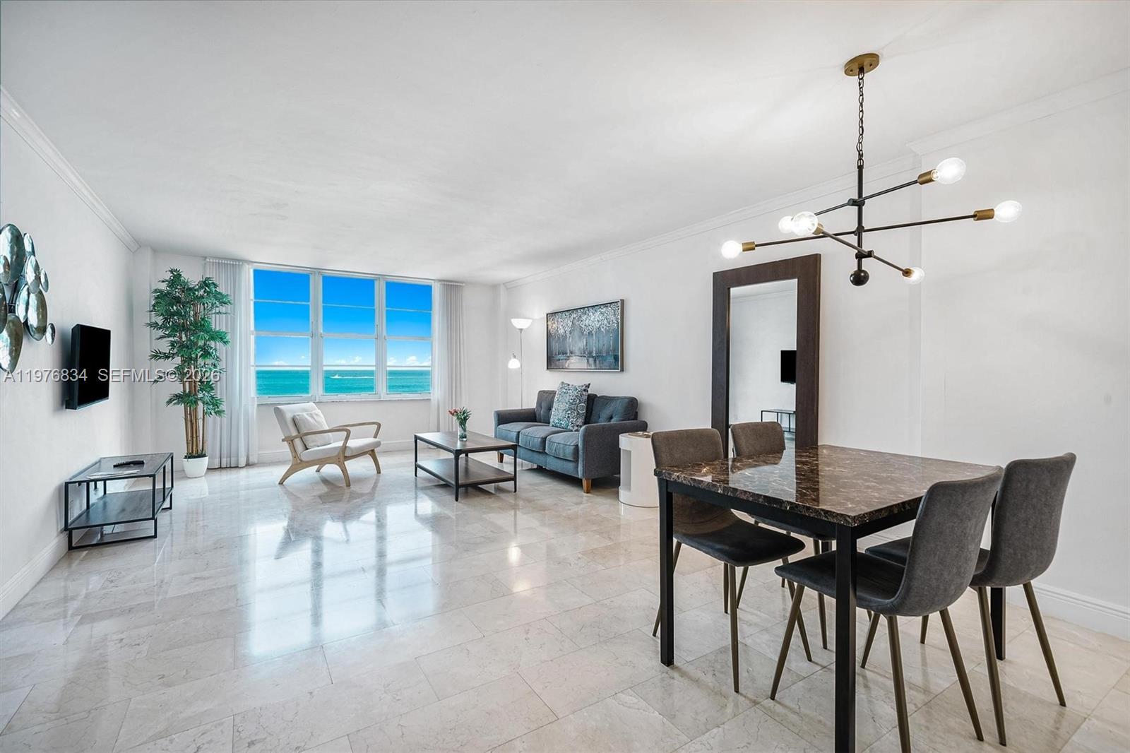 A bright living and dining area features marble floors, modern furniture, and an ocean view — 5101 Collins Ave # 11L, Miami Beach FL 33140, MIAMI BEACH, FL
