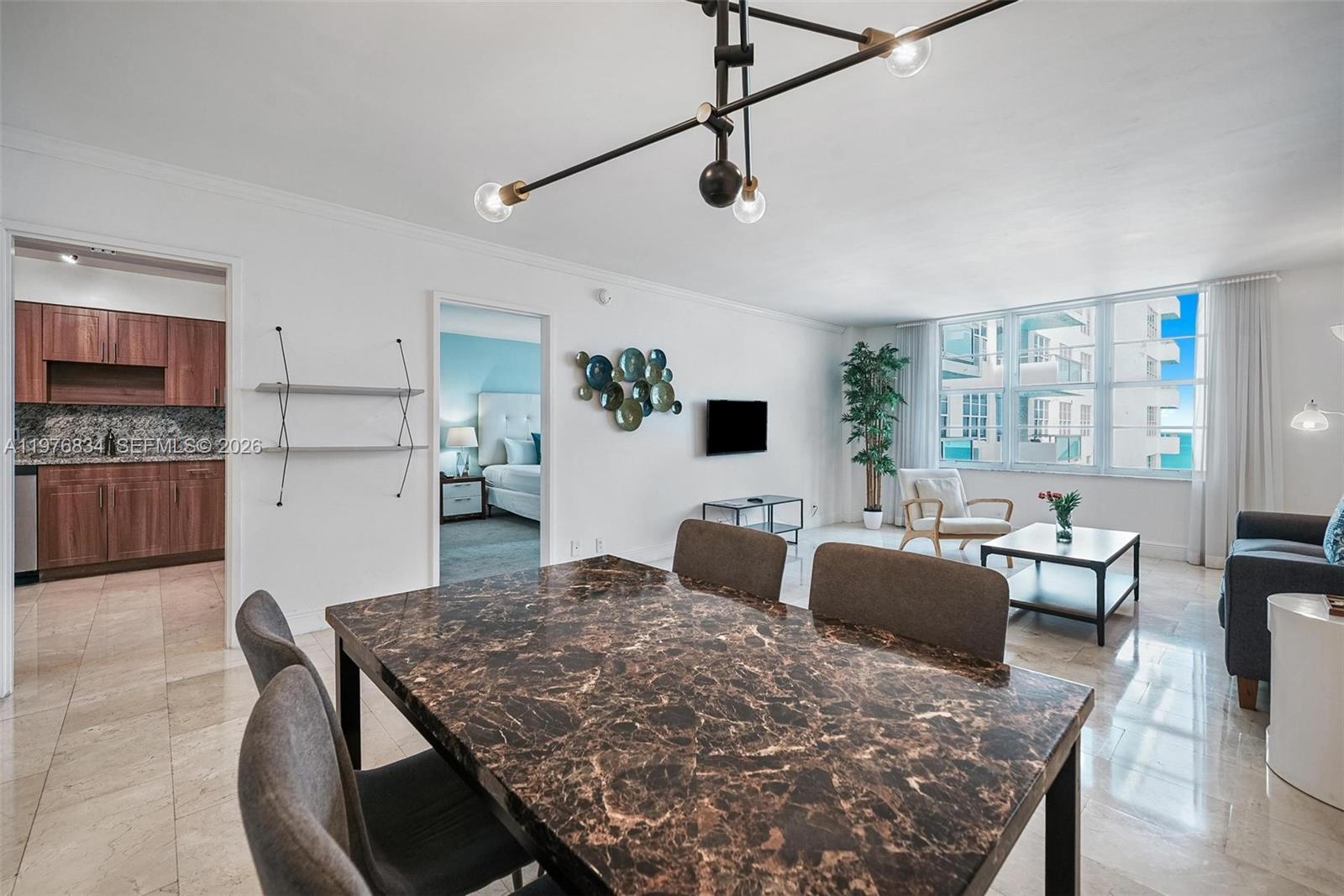 A dining area with a marble table leads into a living room with large windows — 5101 Collins Ave # 11L, Miami Beach FL 33140, MIAMI BEACH, FL