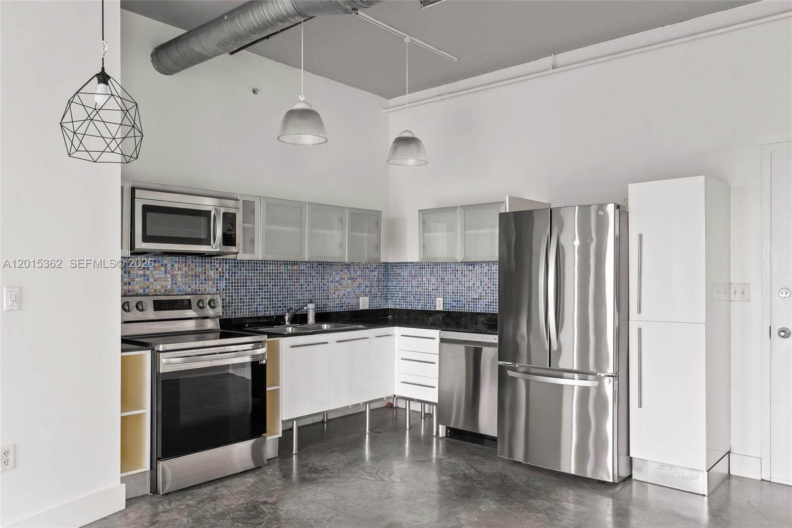 A modern kitchen features stainless steel appliances, white cabinetry, and a blue mosaic tile backsplash — 10 SW South River Dr # 1006, Miami FL 33130, MIAMI, FL