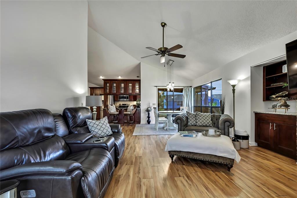 A living room with wood-look flooring, a leather sofa, and an open kitchen in back — 2919 N RIVERS EDGE BOULEVARD UNIT 2919, CRYSTAL RIVER, FL