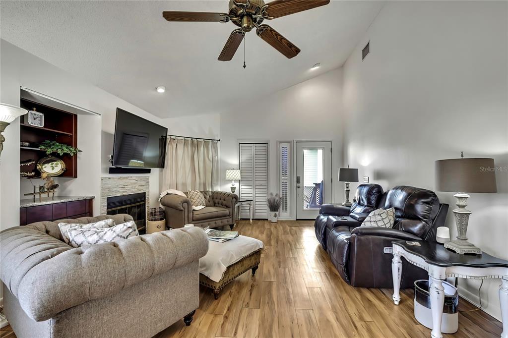A living room features a vaulted ceiling, a stone fireplace, and wood-look flooring — 2919 N RIVERS EDGE BOULEVARD UNIT 2919, CRYSTAL RIVER, FL