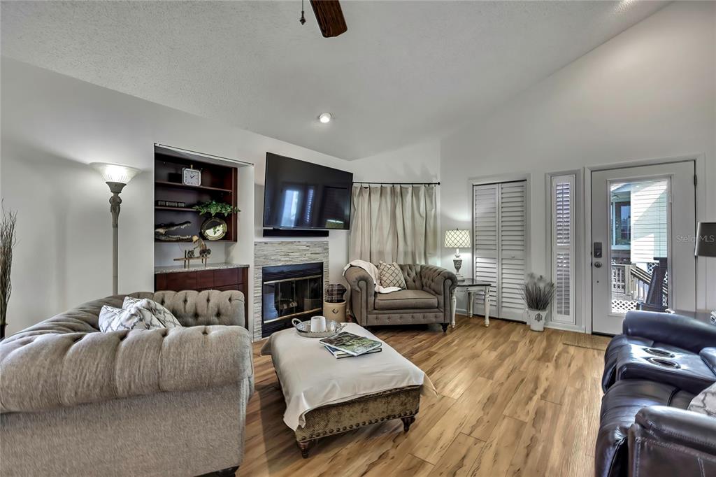A living room features a fireplace, a mounted television, wood-look flooring, and tufted furniture — 2919 N RIVERS EDGE BOULEVARD UNIT 2919, CRYSTAL RIVER, FL