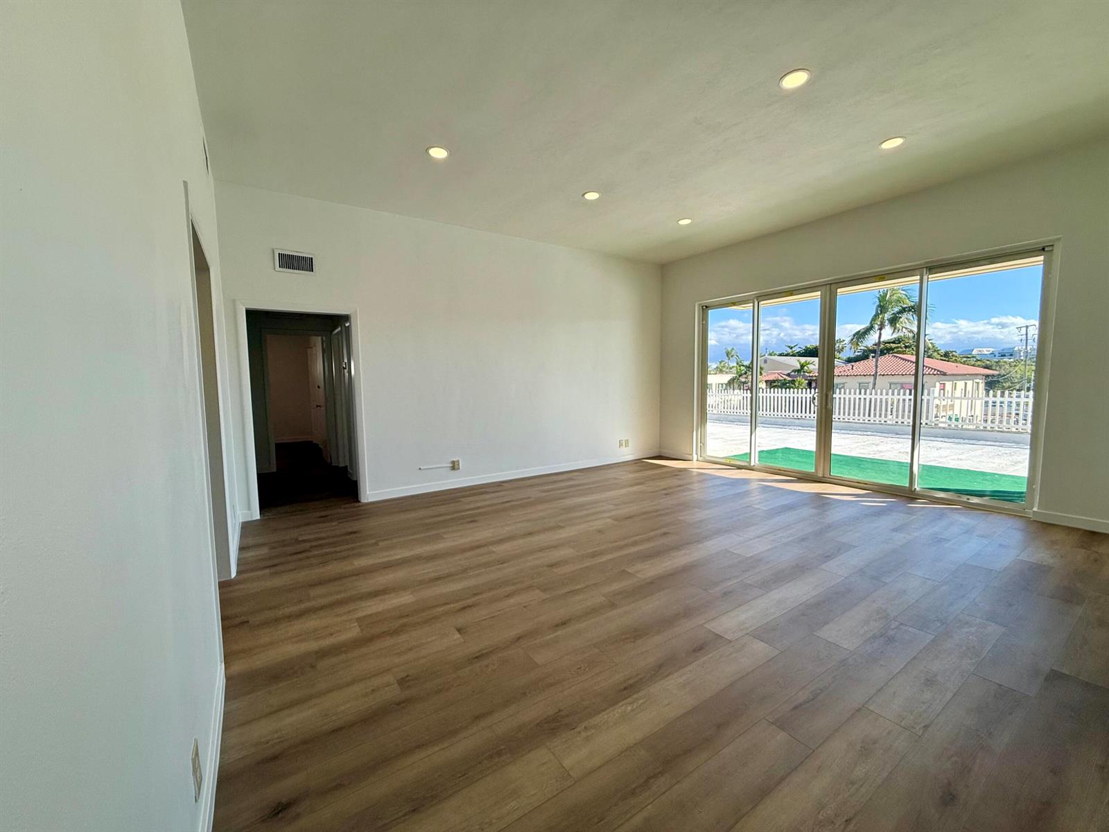 An empty room features light wood-look flooring, recessed lighting, and large sliding glass doors — 1165 E Atlantic Avenue # A, Delray Beach FL 33483, DELRAY BEACH, FL