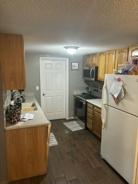A kitchen features wood cabinets, light countertops, a white refrigerator, and dark wood-look flooring — 4801 AVON STREET, LAKE WALES, FL