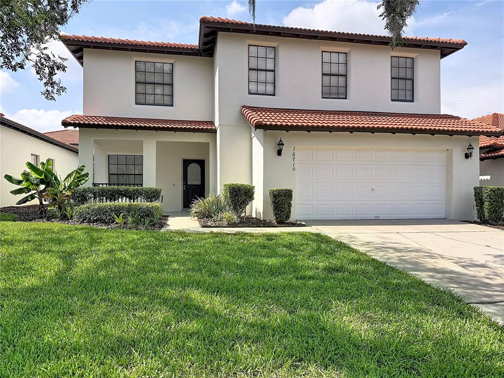 A two-story stucco house with a red tile roof and a two-car garage — 16710 CARIBBEAN BREEZE WAY, CLERMONT, FL