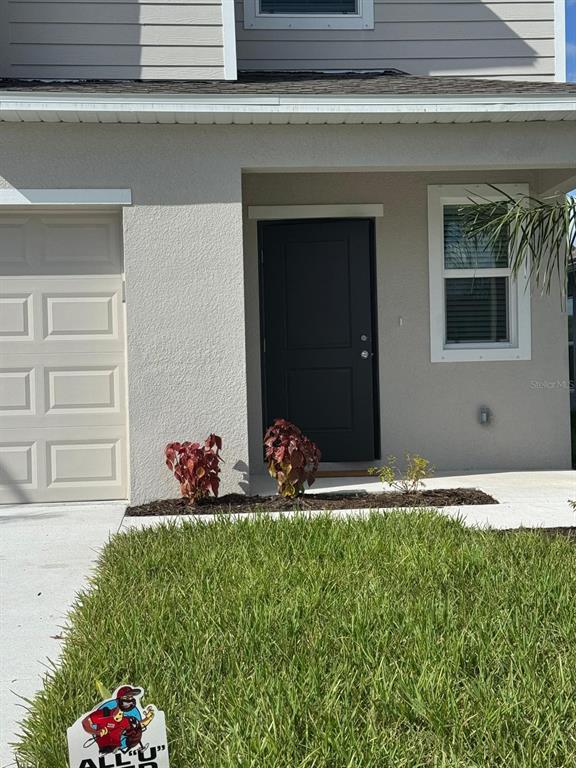The exterior of a house features a beige stucco facade, a dark front door, and a garage — 7111 WEEPING PINE DRIVE, FORT MYERS, FL
