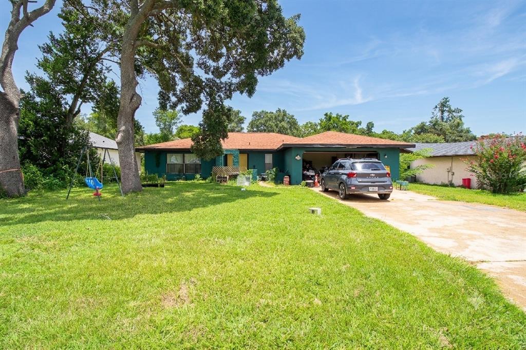 A single-story green house with a two-car garage and a large front lawn — 15791 SW 46TH CIRCLE, OCALA, FL