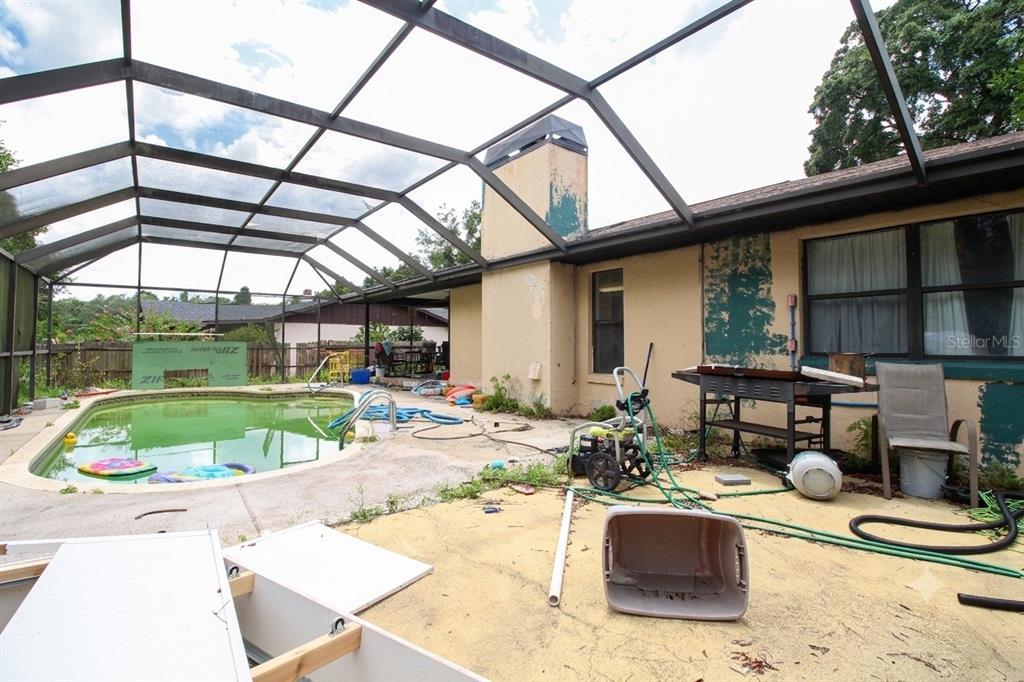 A screened-in patio features a swimming pool, a chimney, and scattered debris — 15791 SW 46TH CIRCLE, OCALA, FL
