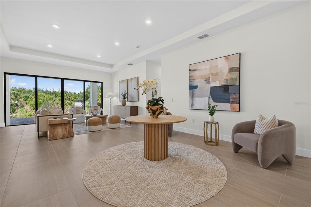A spacious living area features tile flooring, a central round table, and large sliding glass doors — 9668 PRESIDENT CIRCLE, PORT CHARLOTTE, FL
