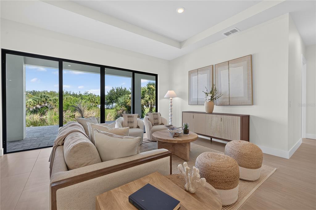A bright living room features a beige sofa, wooden coffee table, and large sliding glass doors — 9668 PRESIDENT CIRCLE, PORT CHARLOTTE, FL