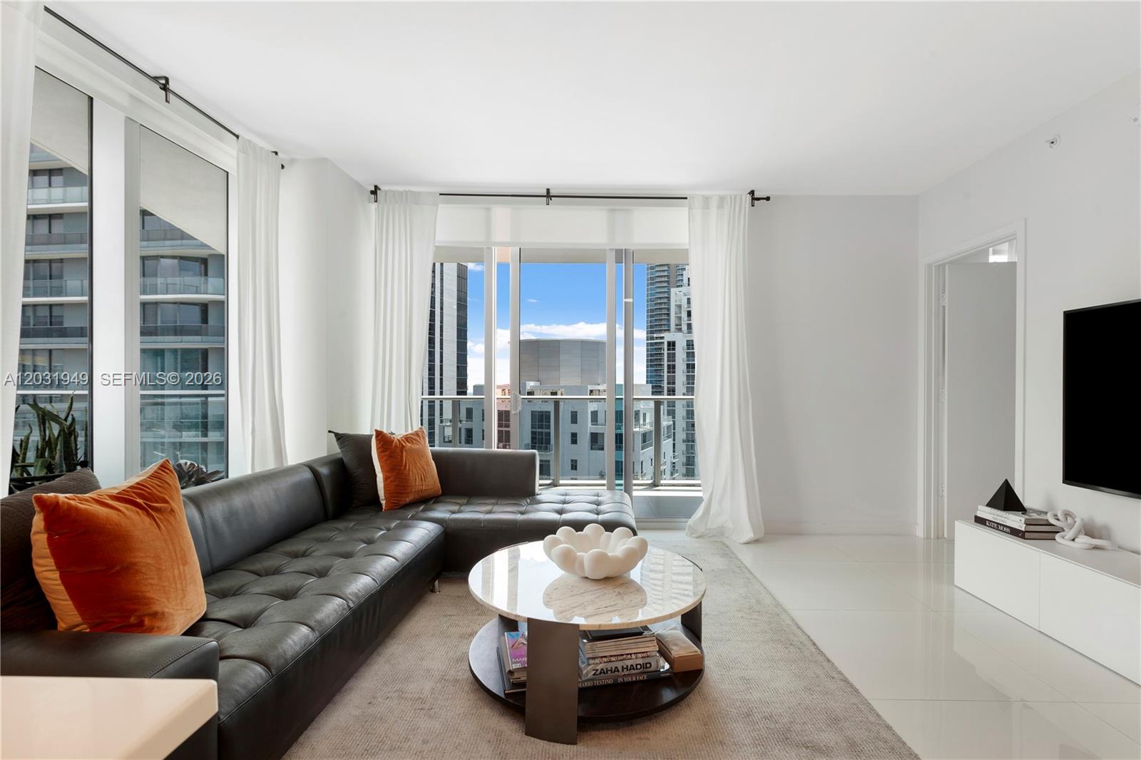 A modern living room features a black leather sectional, a round marble coffee table, and floor-to-ceiling windows — 1100 S Miami Ave # 3810, Miami FL 33130, MIAMI, FL