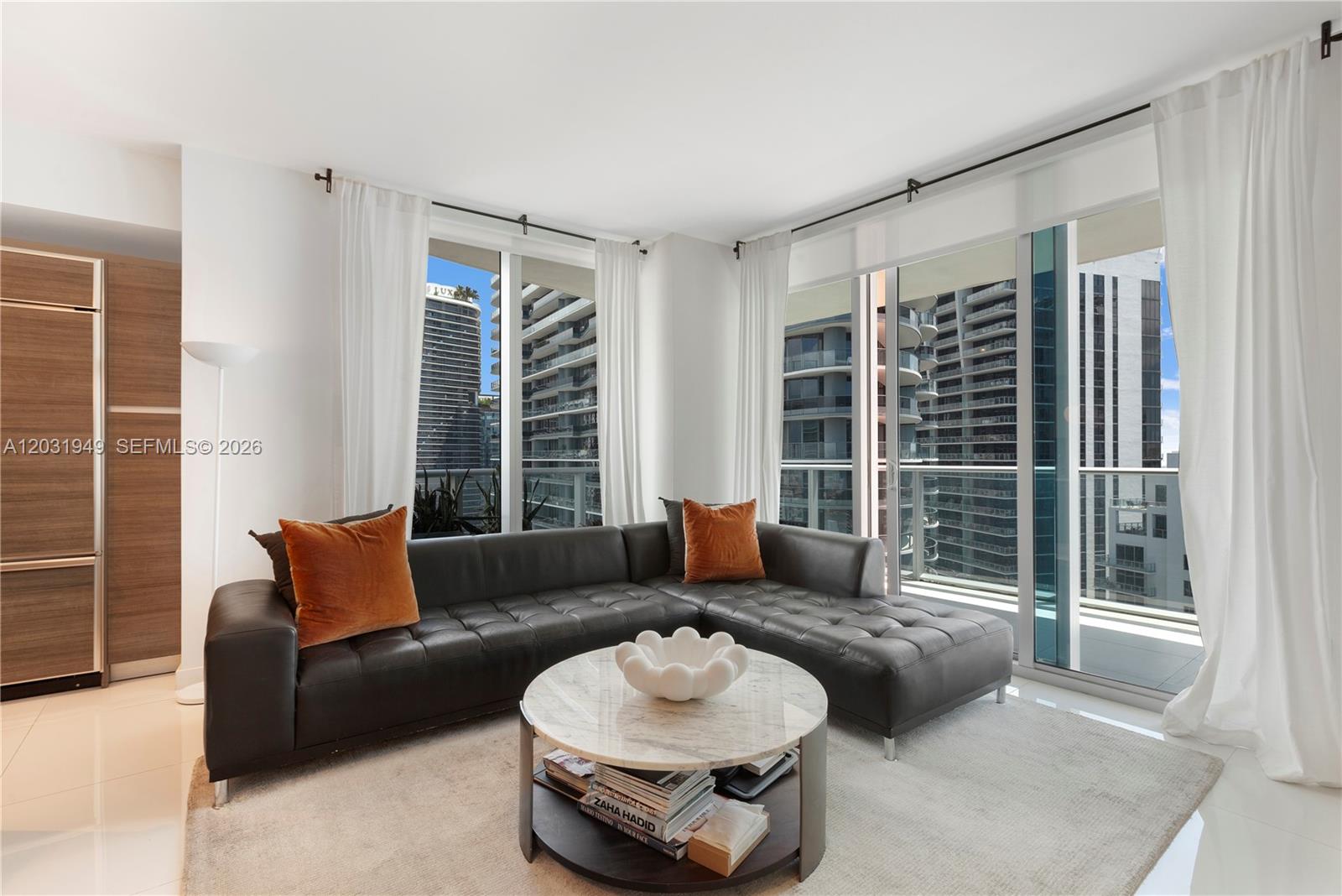A modern living room features a dark leather sectional, marble coffee table, and floor-to-ceiling windows — 1100 S Miami Ave # 3810, Miami FL 33130, MIAMI, FL