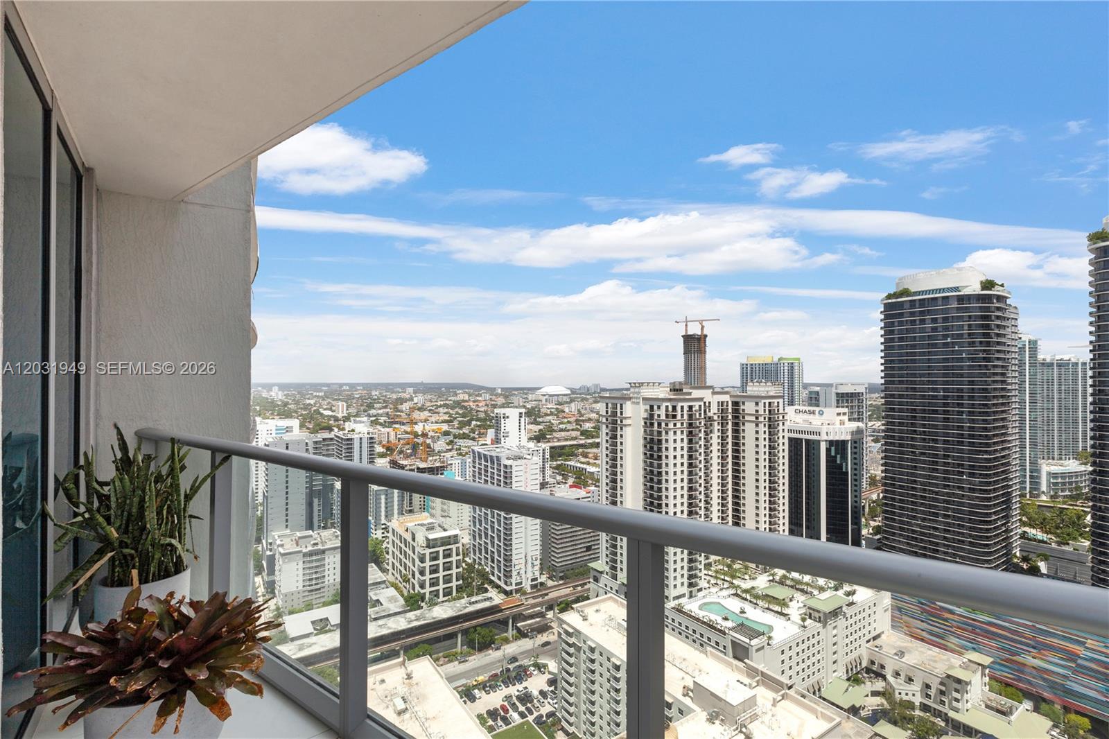 A high-rise balcony overlooks a dense urban cityscape with several tall residential and office buildings — 1100 S Miami Ave # 3810, Miami FL 33130, MIAMI, FL