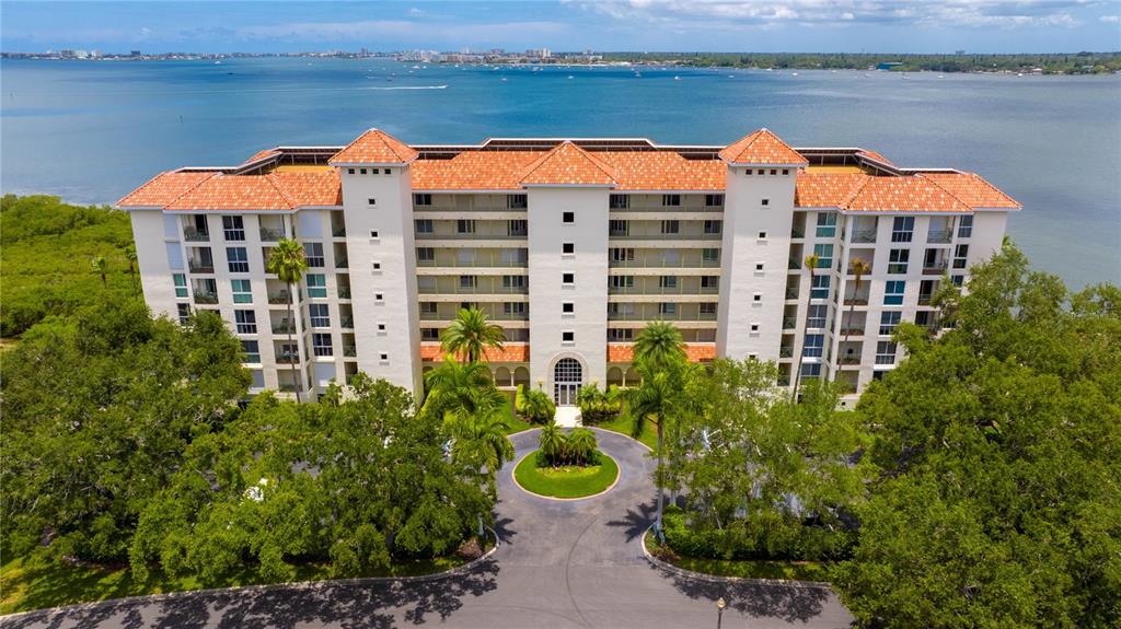 An aerial view of a multi-story apartment building with a red tile roof near water — 4717 DOLPHIN CAY LANE S UNIT 507, ST PETERSBURG, FL