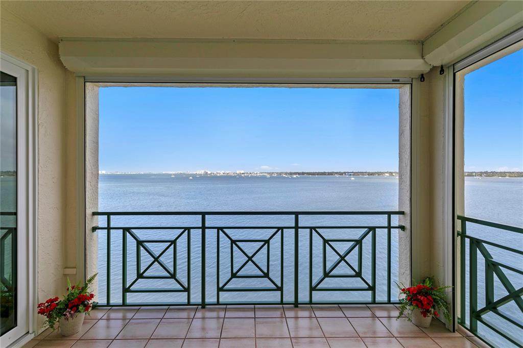A tiled balcony with a green metal railing overlooks a large body of water — 4717 DOLPHIN CAY LANE S UNIT 507, ST PETERSBURG, FL