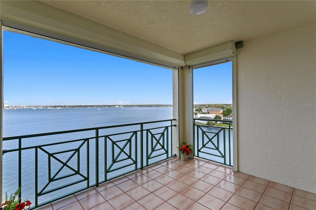 A tiled balcony features a green metal railing overlooking a large body of water — 4717 DOLPHIN CAY LANE S UNIT 507, ST PETERSBURG, FL