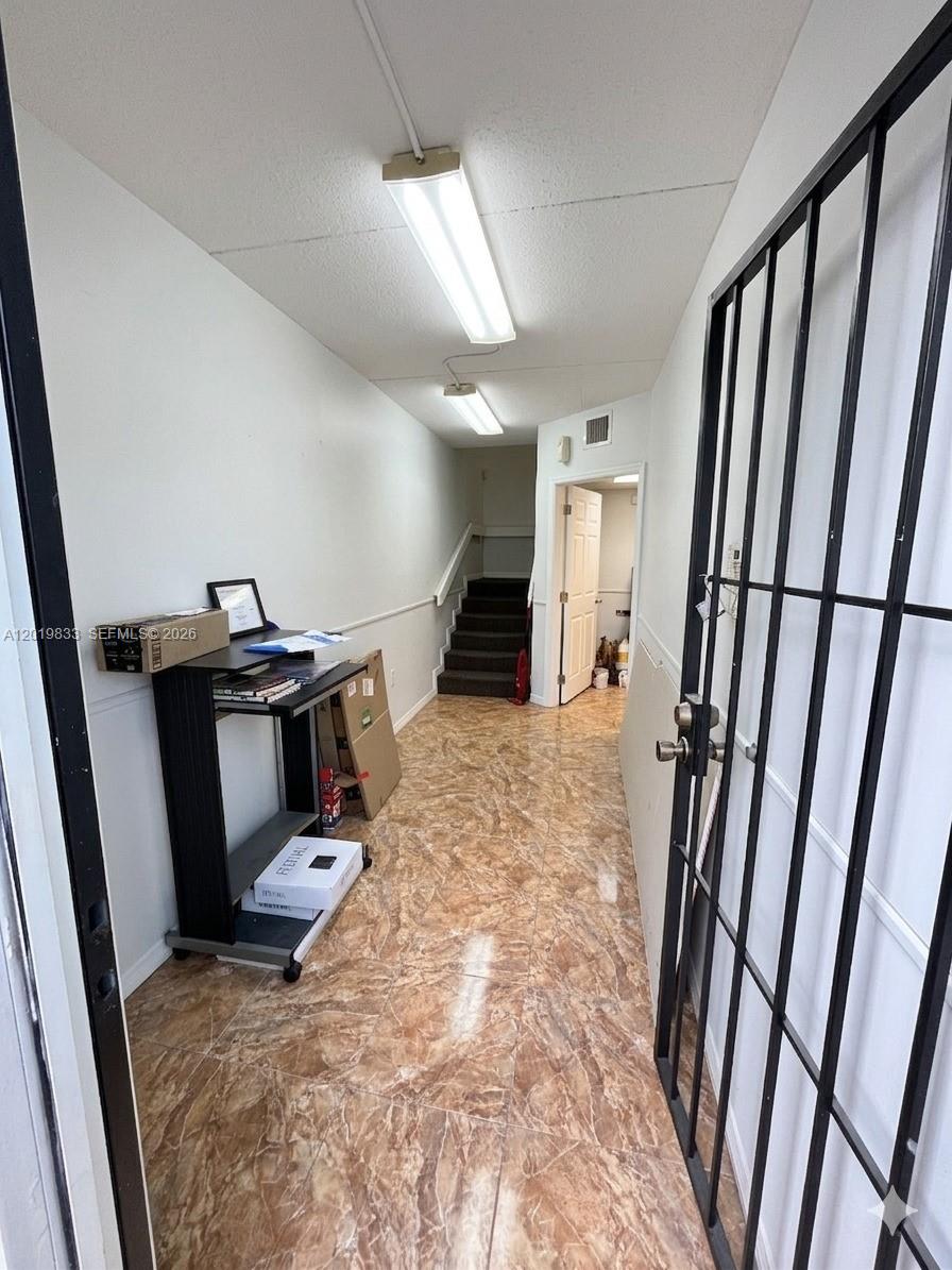 A narrow hallway features brown marble-patterned tile flooring, white walls, and a metal security gate — 16115 SW 117th Ave # A13, Miami FL 33177, MIAMI, FL