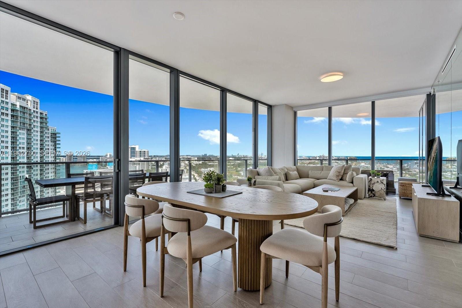A modern living and dining area features floor-to-ceiling windows, light wood floors, and a balcony — 500 Alton Rd # 2205, Miami Beach FL 33139, MIAMI BEACH, FL