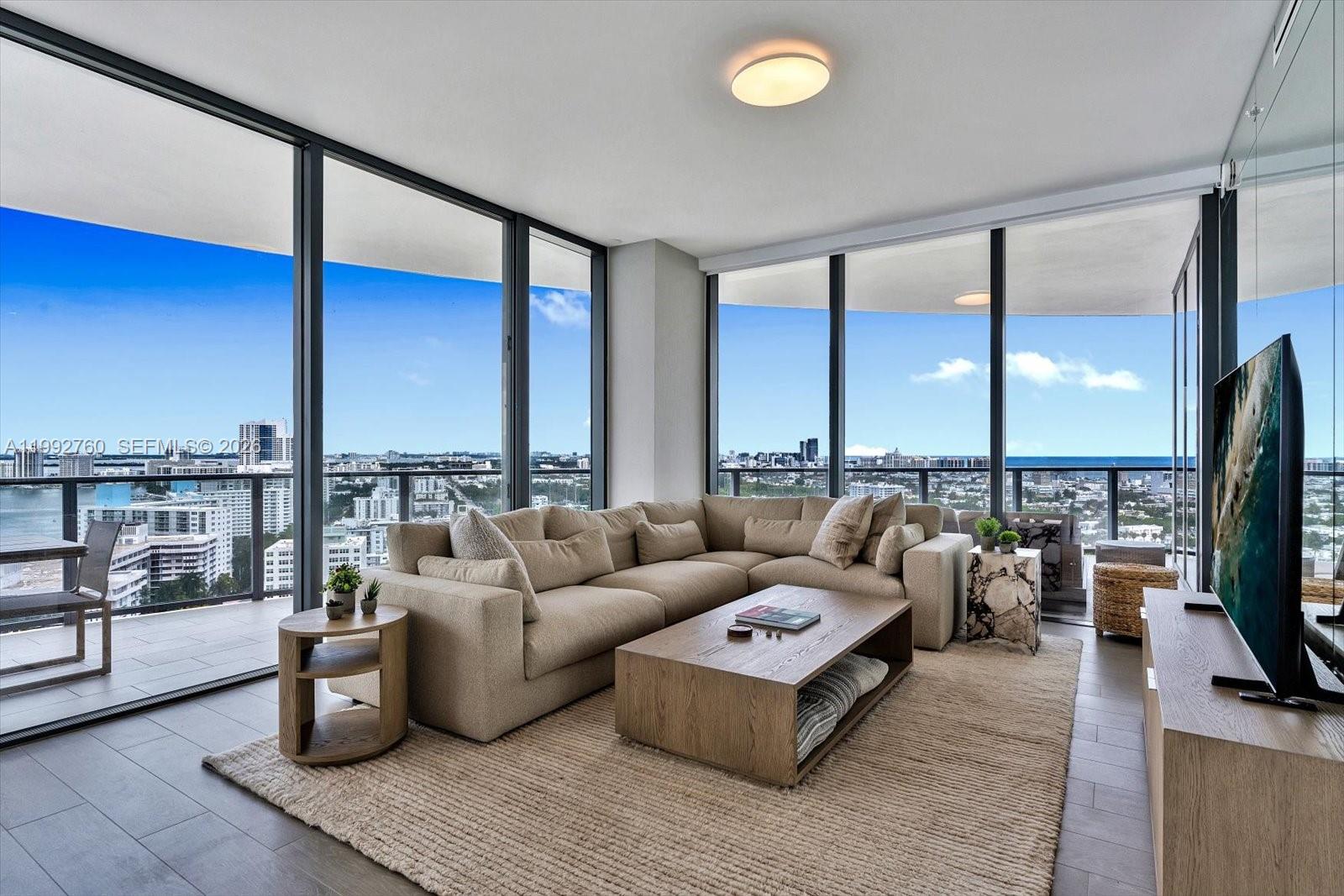 A modern living room features a beige sectional sofa, wood coffee table, and floor-to-ceiling windows — 500 Alton Rd # 2205, Miami Beach FL 33139, MIAMI BEACH, FL