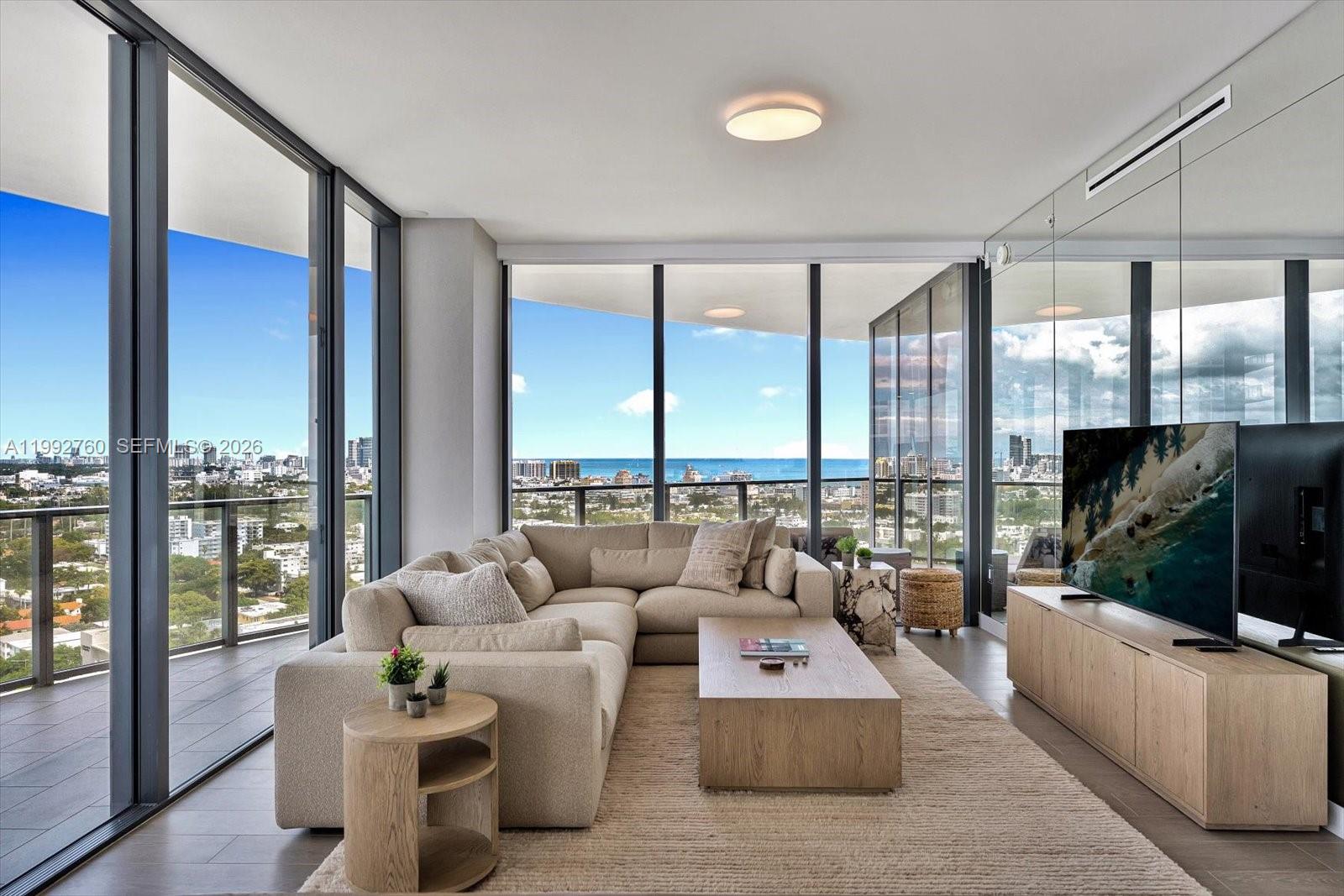 A modern living room features a beige sectional sofa, wood coffee table, and floor-to-ceiling windows — 500 Alton Rd # 2205, Miami Beach FL 33139, MIAMI BEACH, FL