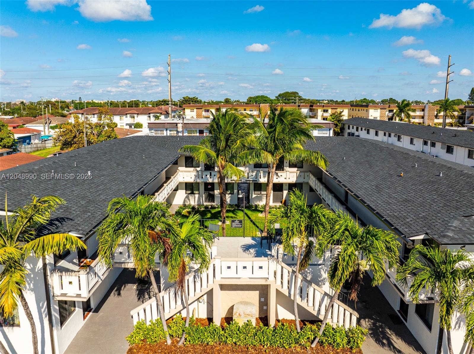 An aerial view shows a U-shaped apartment complex with a central courtyard and palm trees — 1345 W 28th St # 4, Hialeah FL 33010, HIALEAH, FL