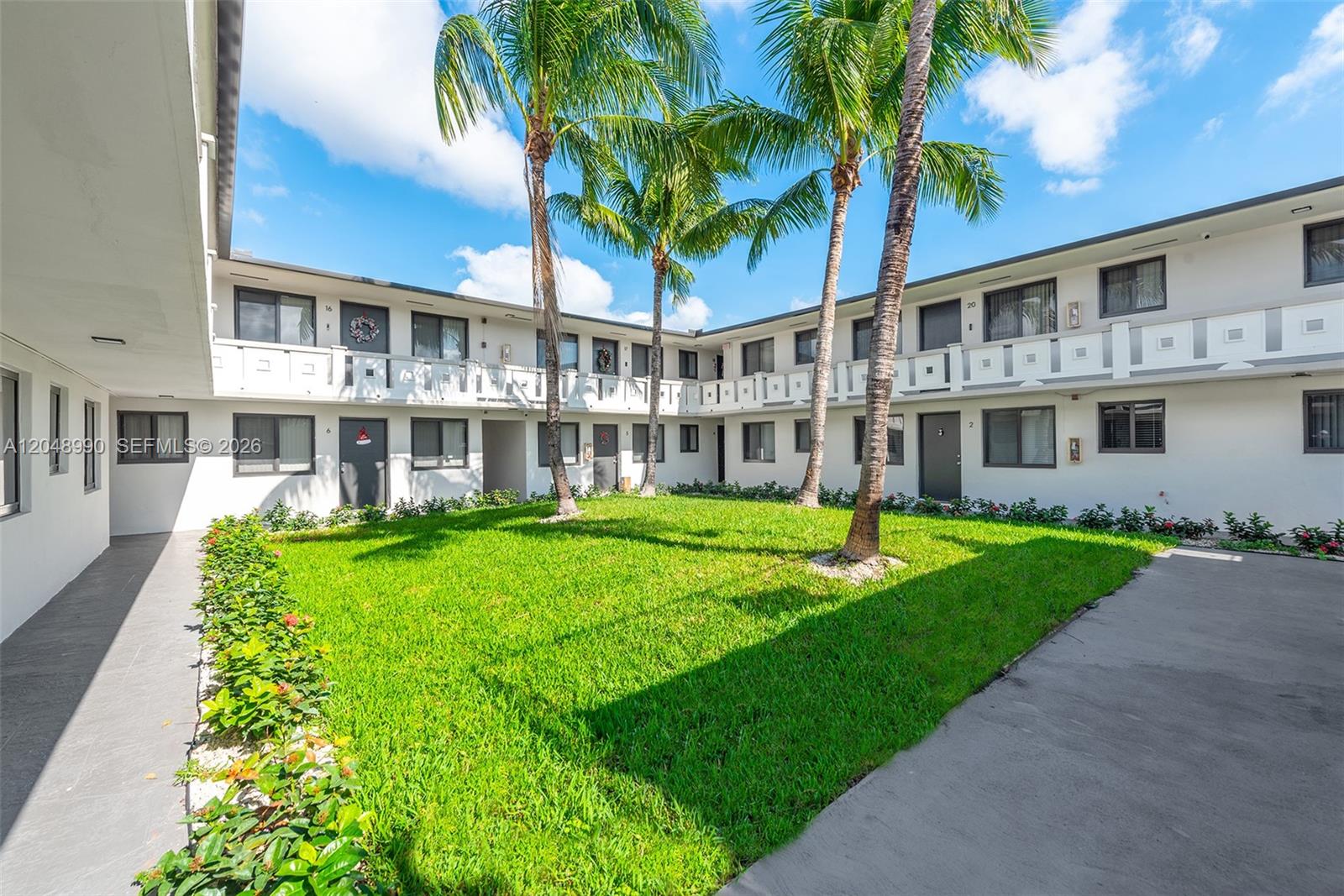 A two-story apartment complex surrounds a central grassy courtyard with palm trees — 1345 W 28th St # 4, Hialeah FL 33010, HIALEAH, FL