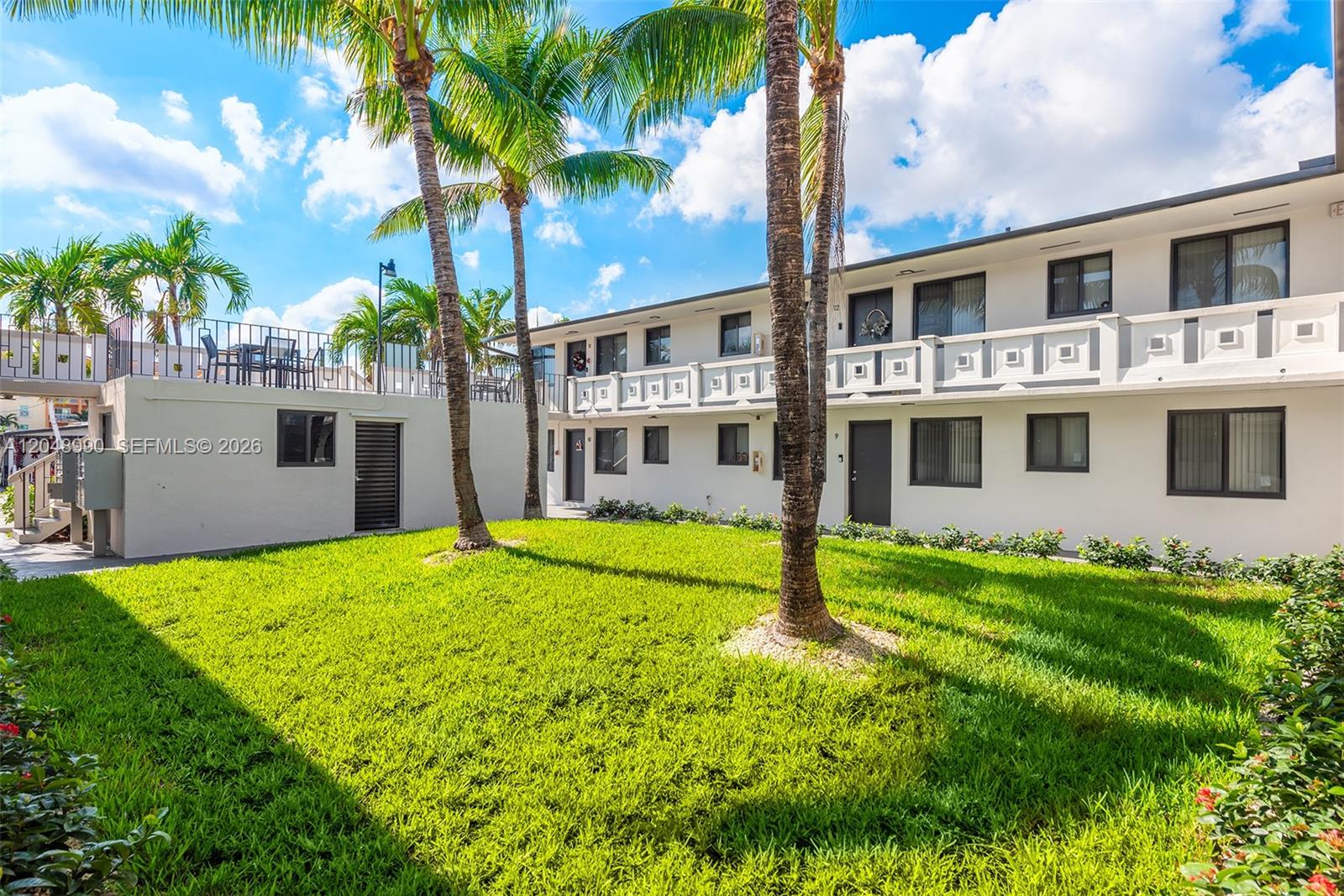 A two-story apartment building features a grassy courtyard with palm trees and exterior walkways — 1345 W 28th St # 4, Hialeah FL 33010, HIALEAH, FL