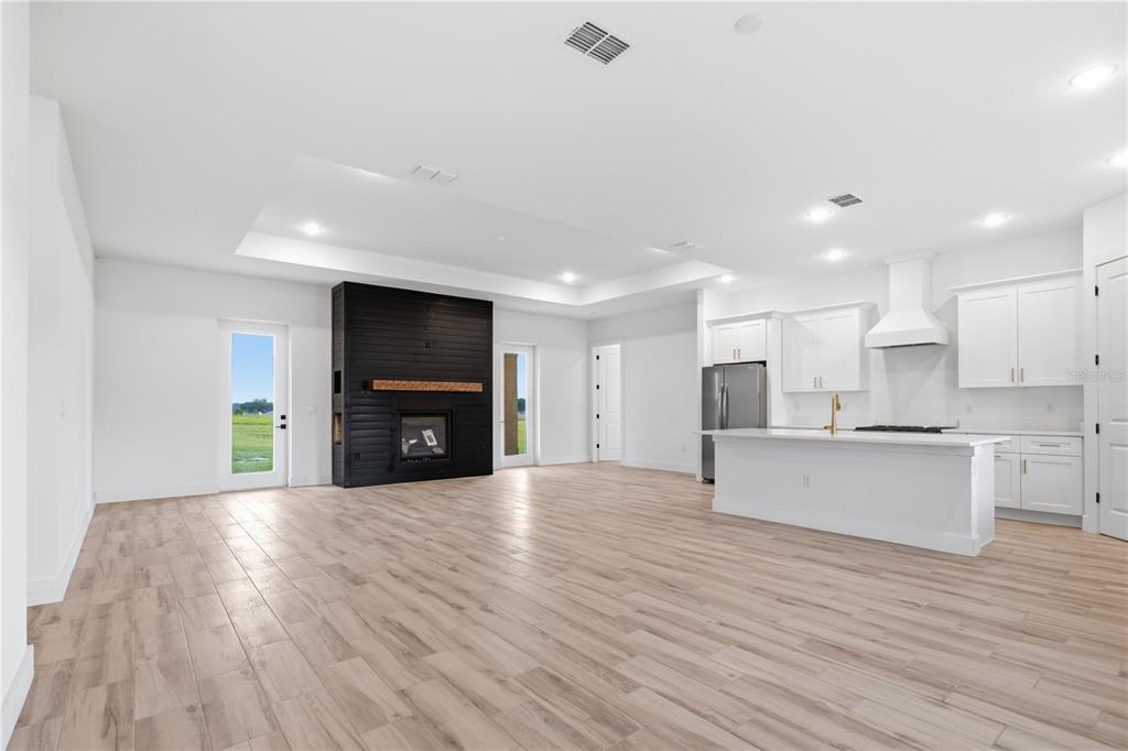 An open-concept living room and kitchen featuring a black fireplace and light wood-look flooring — 3890 SE 139 TERRACE, MORRISTON, FL