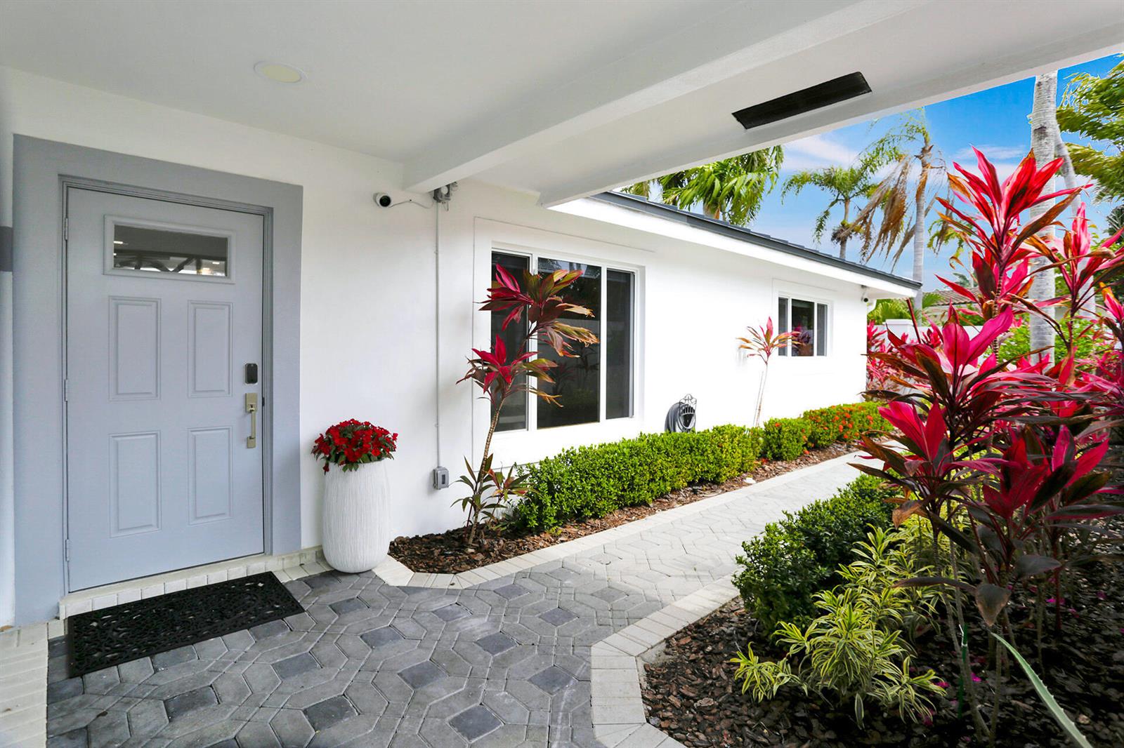 A paved walkway leads to a light gray front door beside a white house exterior — 201 SE 11th Street, Pompano Beach FL 33060, POMPANO BEACH, FL