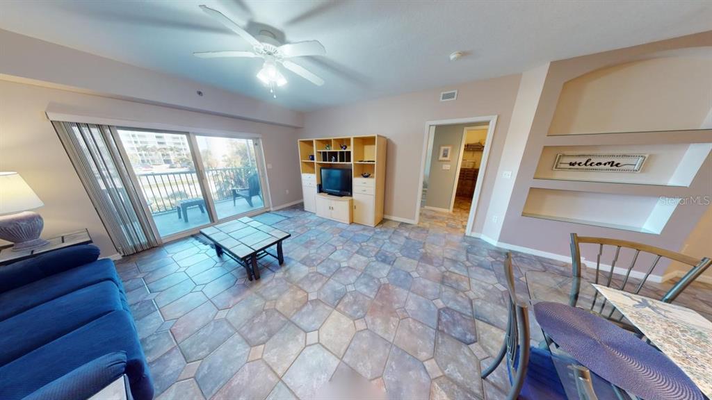 A living room with tile flooring, a ceiling fan, a balcony, and built-in wall shelving — 5300 S ATLANTIC AVENUE UNIT 23003, NEW SMYRNA BEACH, FL