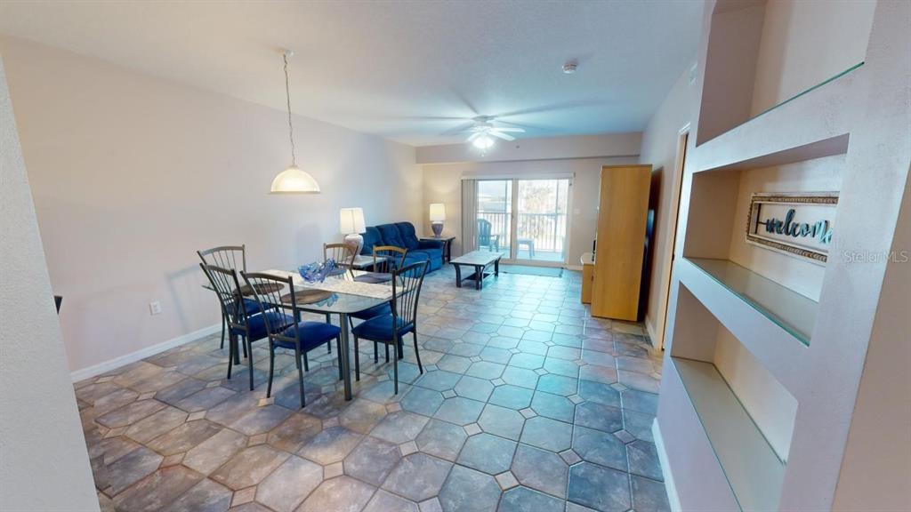 An open-concept living and dining area features tile flooring, a glass dining table, and balcony access — 5300 S ATLANTIC AVENUE UNIT 23003, NEW SMYRNA BEACH, FL
