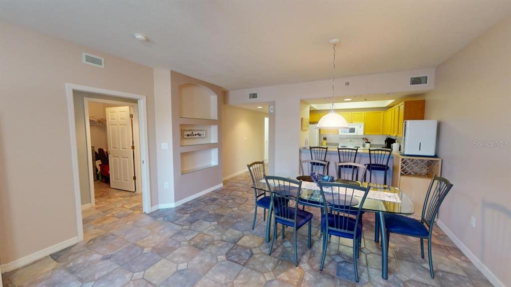 A dining area with a glass table and chairs sits adjacent to a kitchen counter — 5300 S ATLANTIC AVENUE UNIT 23003, NEW SMYRNA BEACH, FL