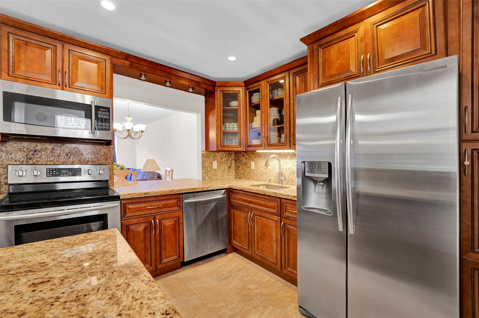A kitchen features wood cabinets, granite countertops, and stainless steel appliances — 410 SE 2nd St # 220, Hallandale Beach FL 33009, HALLANDALE BEACH, FL