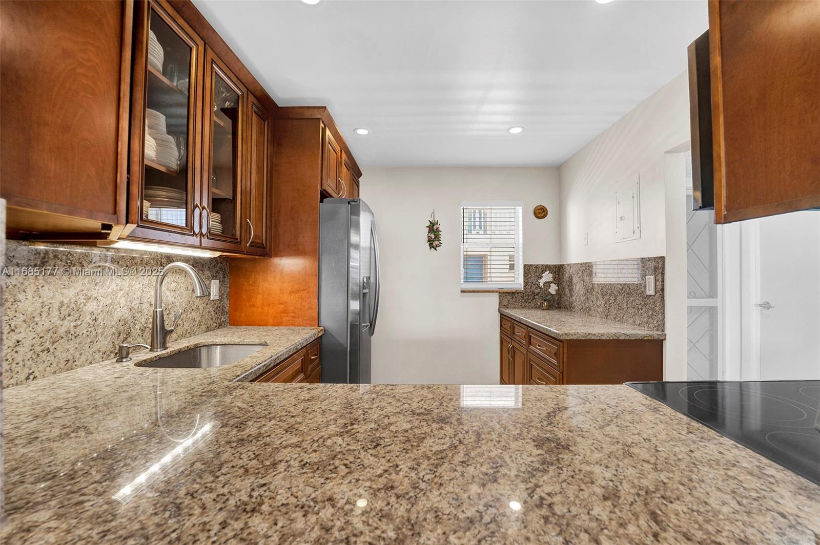 This kitchen features wood cabinets, granite countertops, stainless steel appliances, and a window — 410 SE 2nd St # 220, Hallandale Beach FL 33009, HALLANDALE BEACH, FL
