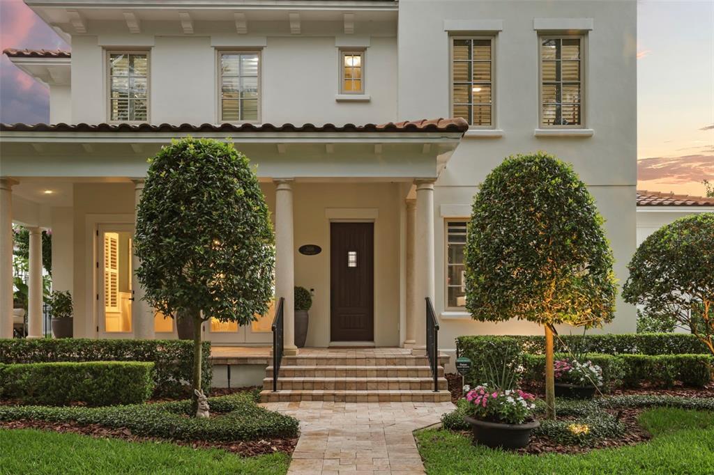 A two-story house exterior features a covered porch, stone steps, and manicured landscaping — 2656 MEETING PLACE, ORLANDO, FL