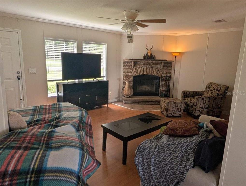 A living room features a fireplace, a ceiling fan, a television, and patterned furniture — 25417 OLD BELLAMY ROAD, HIGH SPRINGS, FL