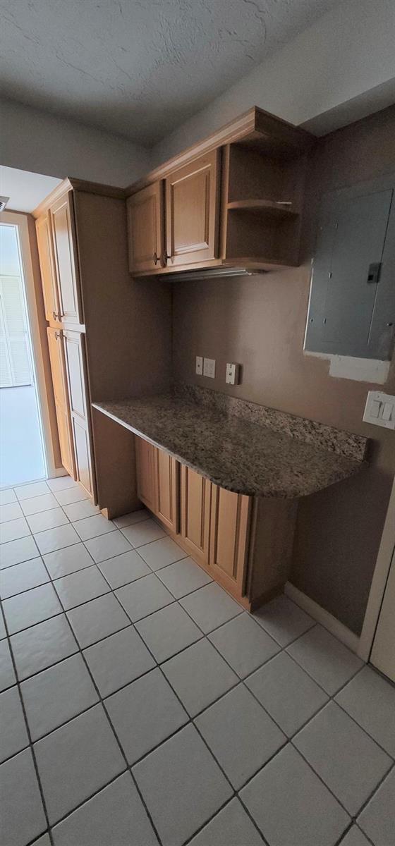 A kitchen area features light wood cabinets, a granite countertop, and white floor tiles — 2425 Presidential Way # 402, West Palm Beach FL 33401, WEST PALM BEACH, FL