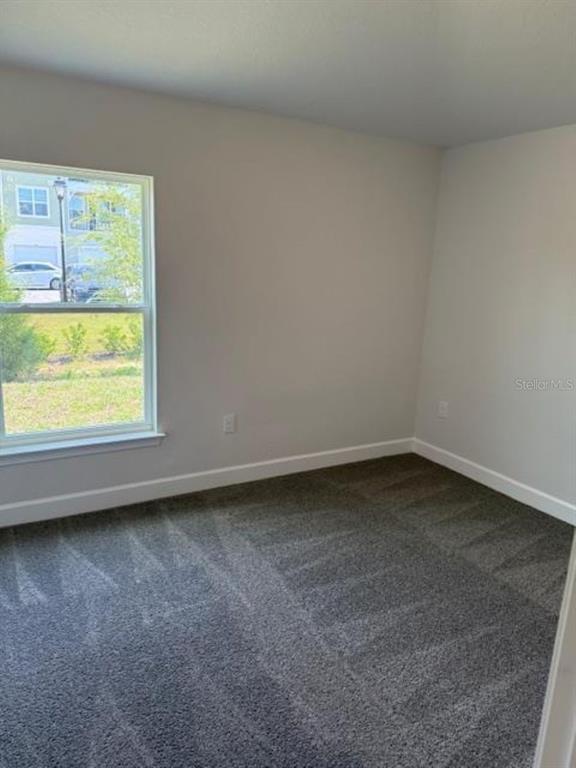 An empty bedroom with gray carpet, light-colored walls, and a window overlooking a parking area — 2396 NW 23RD AVENUE, OCALA, FL