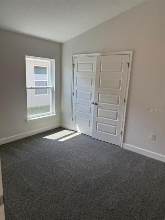 A bedroom with gray carpet, a single window, and white double closet doors — 2396 NW 23RD AVENUE, OCALA, FL