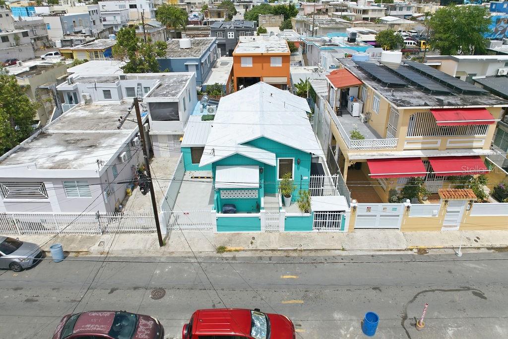 An aerial view shows a turquoise house situated between a grey building and a yellow house — 115 SANTA CECILIA, SAN JUAN, PR