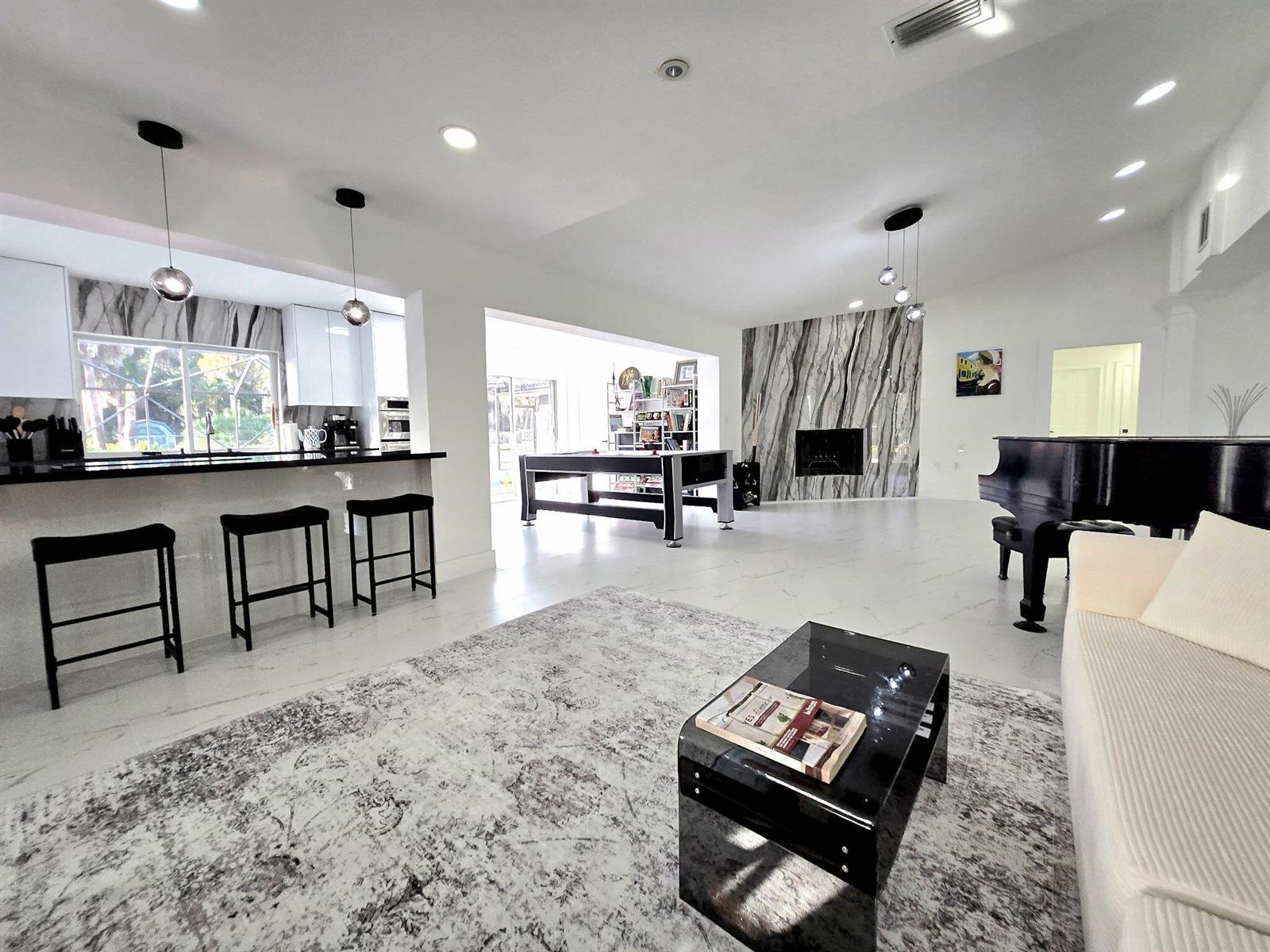 A spacious open-concept living area features a kitchen, pool table, fireplace, and grand piano — 12231 Areaca Drive, Wellington FL 33414, WELLINGTON, FL