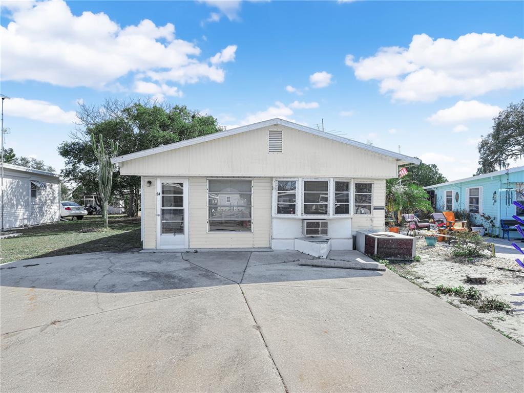 A single-story mobile home with light siding features a concrete driveway and a front entrance — 31 STONEFLY CIRCLE, LAKE WALES, FL