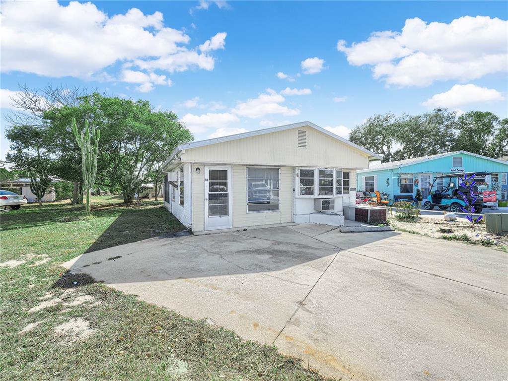A single-story house with a concrete driveway, white siding, and a large cactus nearby — 31 STONEFLY CIRCLE, LAKE WALES, FL
