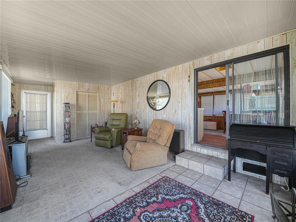 A sunroom features wood-paneled walls, a mix of carpet and tile flooring, and two armchairs — 31 STONEFLY CIRCLE, LAKE WALES, FL