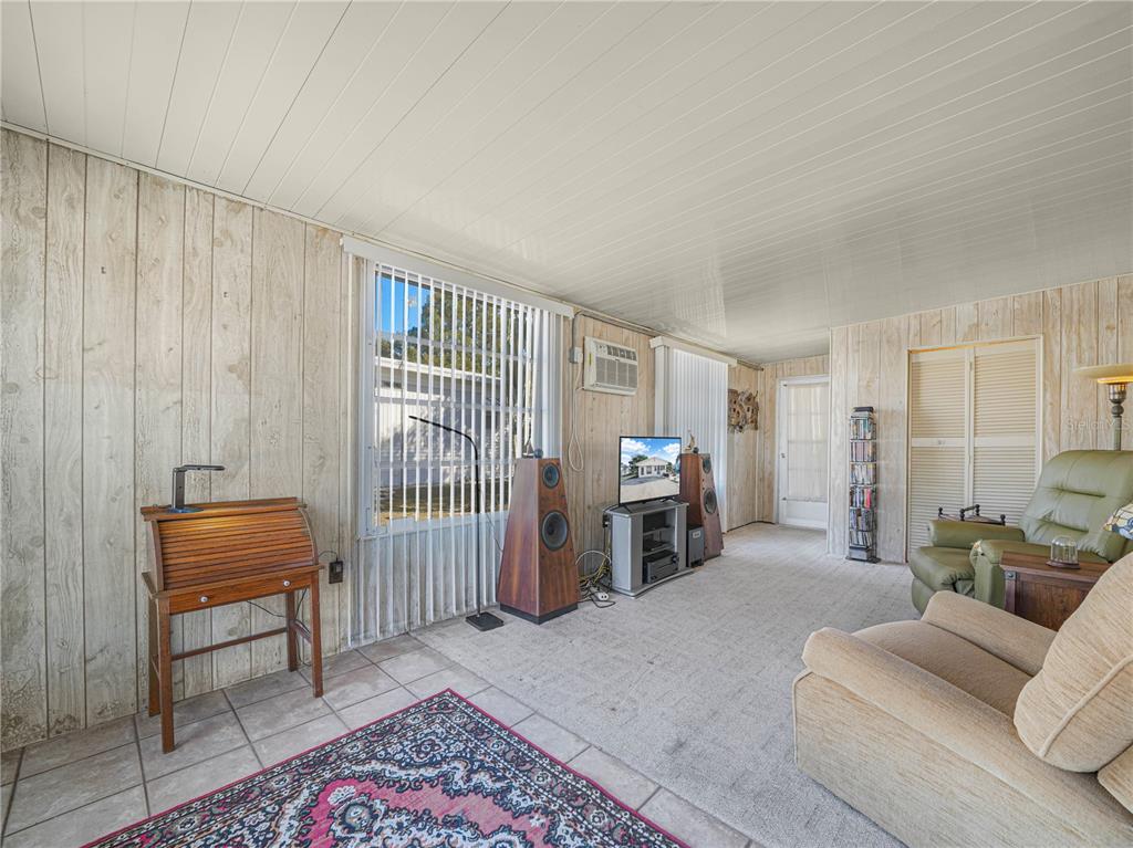 A living room features wood-paneled walls, a tile floor with an area rug, and large speakers — 31 STONEFLY CIRCLE, LAKE WALES, FL