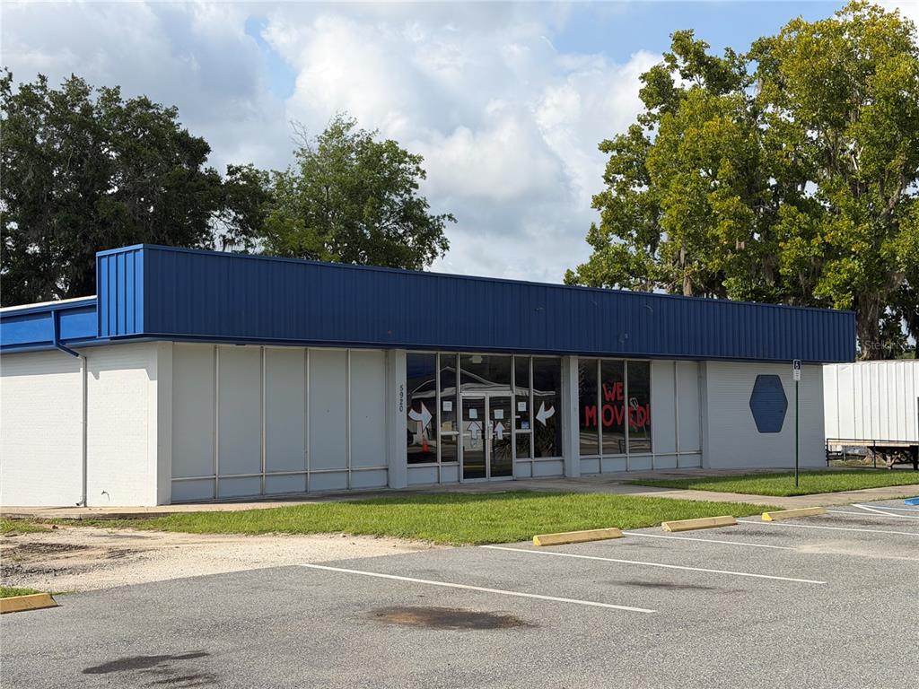 A single-story commercial building with a blue metal roof and a "We Moved" sign — 5920 SE HAMES ROAD, BELLEVIEW, FL