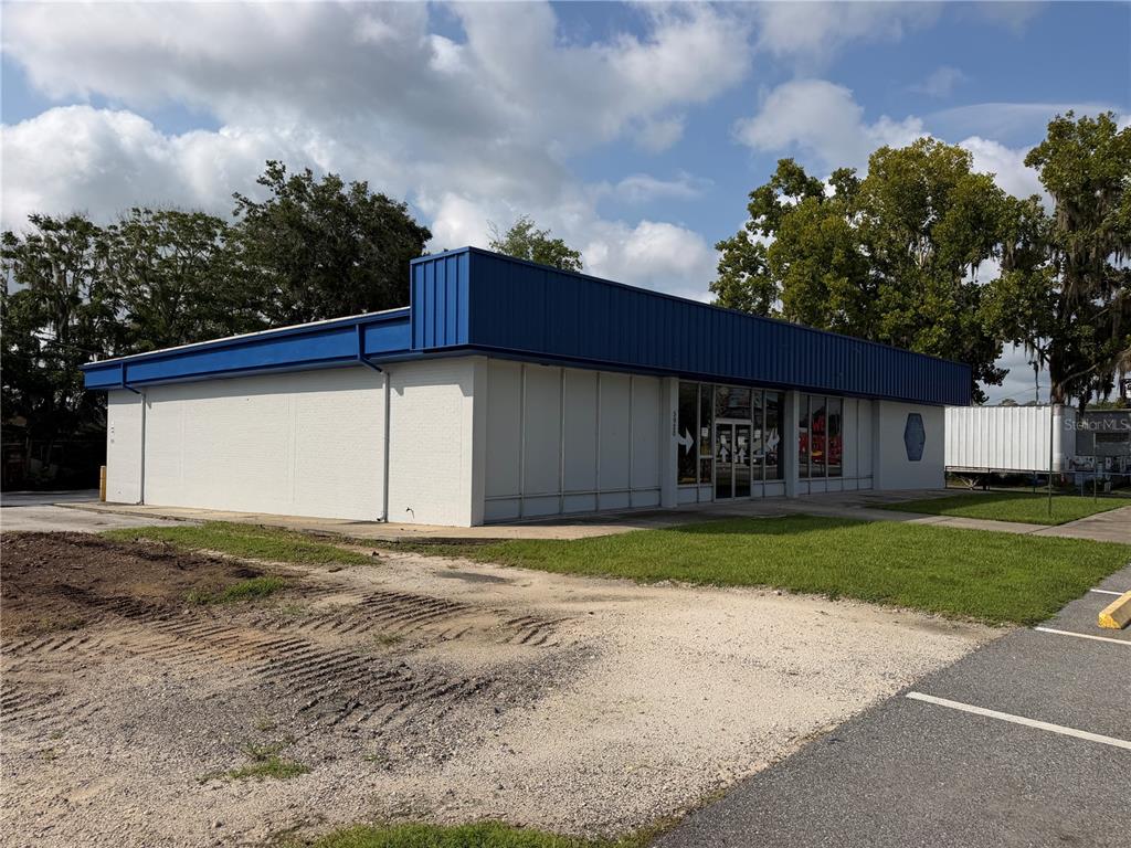A single-story commercial building with white brick walls and a blue metal roof fascia — 5920 SE HAMES ROAD, BELLEVIEW, FL