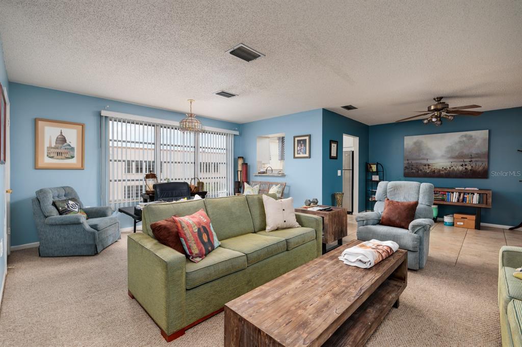 A living room features a green sofa, two armchairs, a wooden coffee table, and blue walls — 5623 80TH STREET N UNIT 504, ST PETERSBURG, FL